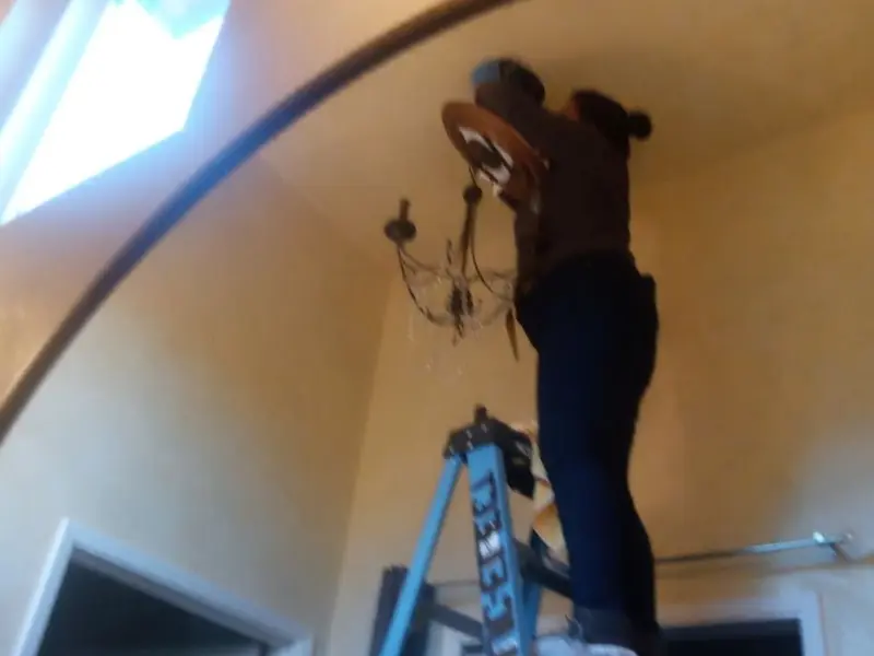 Electrician installing a chandelier in a Grants residence